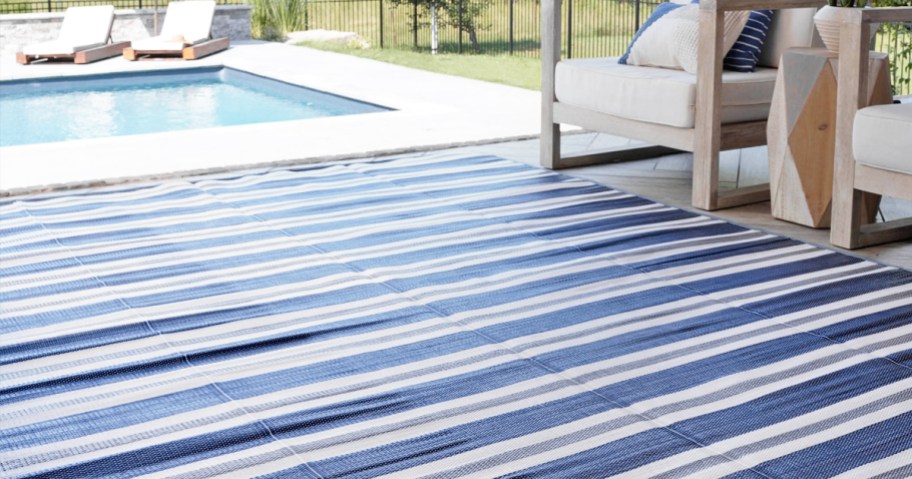 blue and white striped area rug with patio chairs and pool in distance