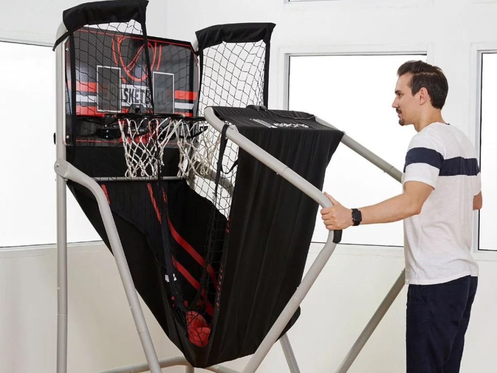 man folding up an indoor basketball arcade game