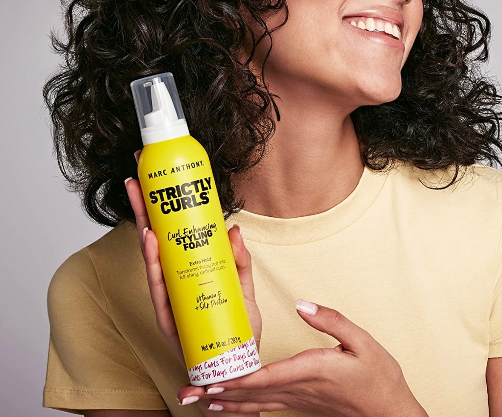 woman holding bottle of Marc Anthony Strictly Curl Curl Enhancing Styling Foam