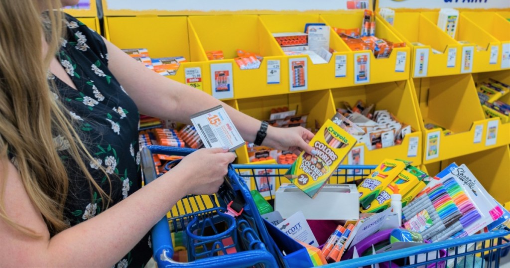 woman holding coupon and filling shopping cart with school supplies