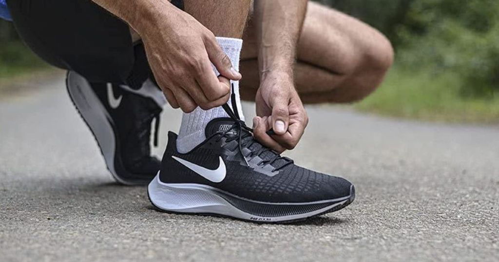person tying a Nike shoe