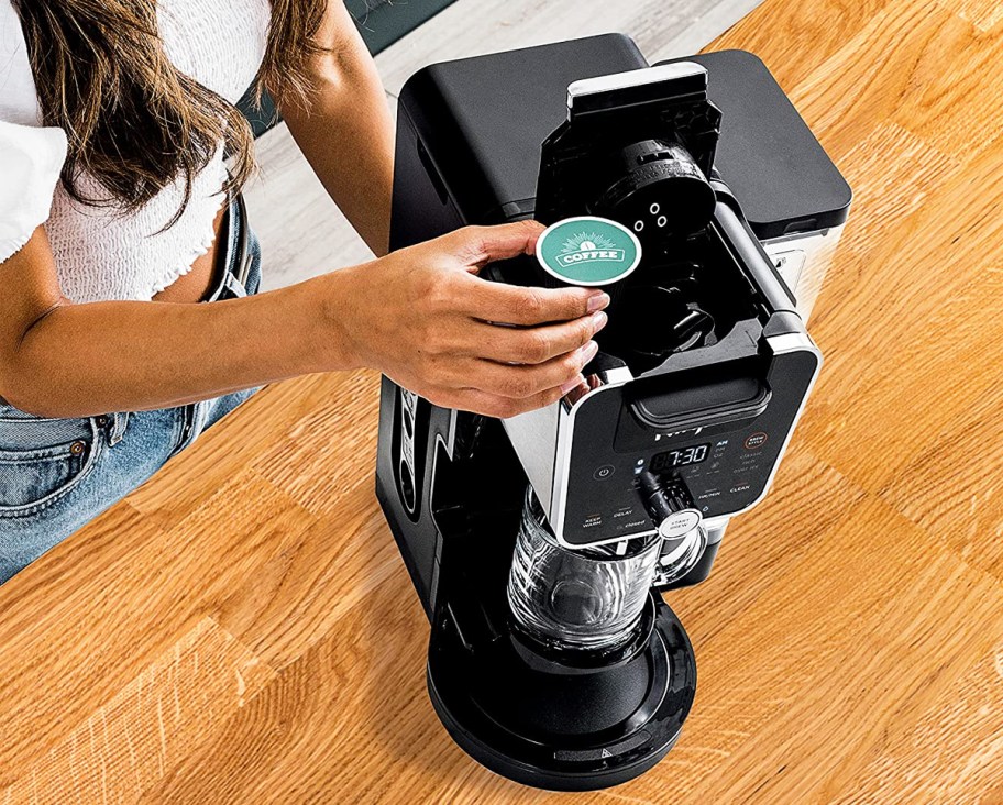 woman placing k-cup into coffee maker
