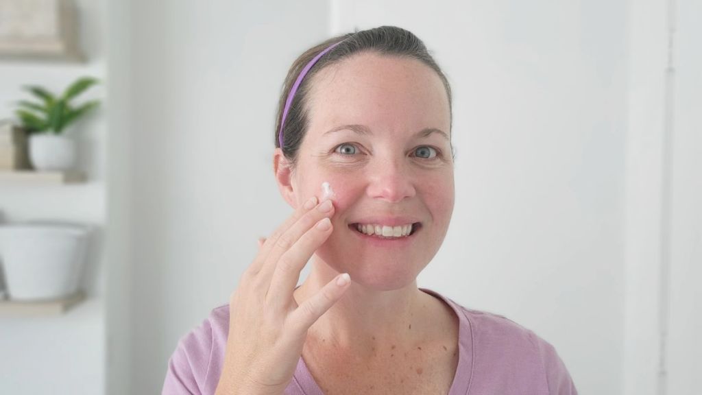 woman rubbing a moisturizer on her cheek