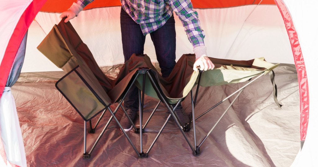 man folding away cot inside tent