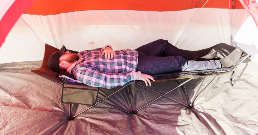 man laying on cot inside tent