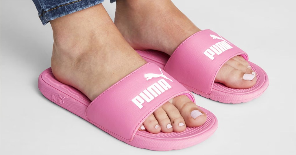 woman wearing a pair of pink and white puma slides