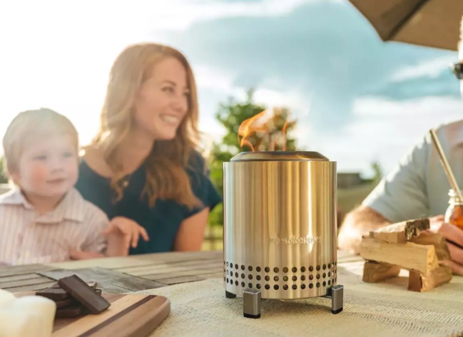 Woman and a kid sitting at a table with a tabletop fire stove on it
