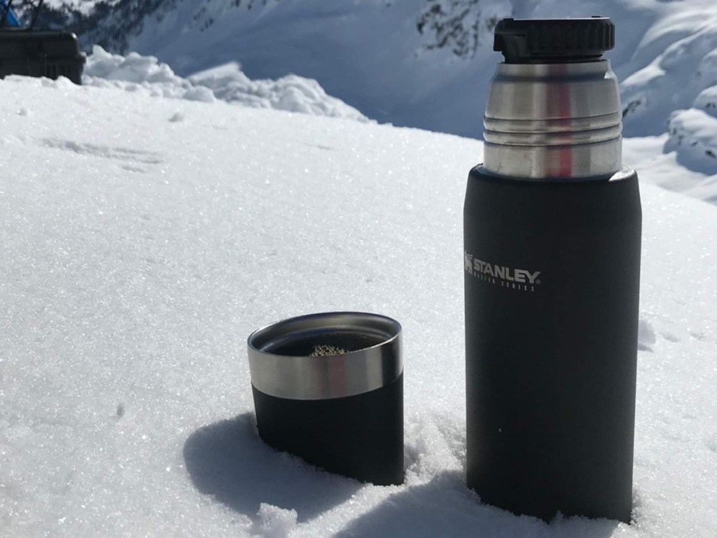 thermos and lid full of coffee in snow