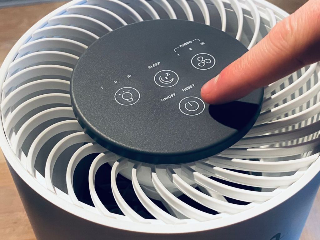 hand touching top of air purifier