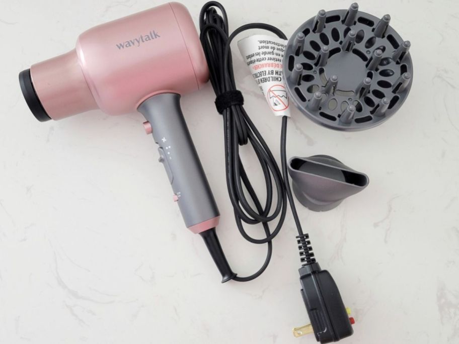 pink Wavytalk Hair Dryer laying on counter next to attachments