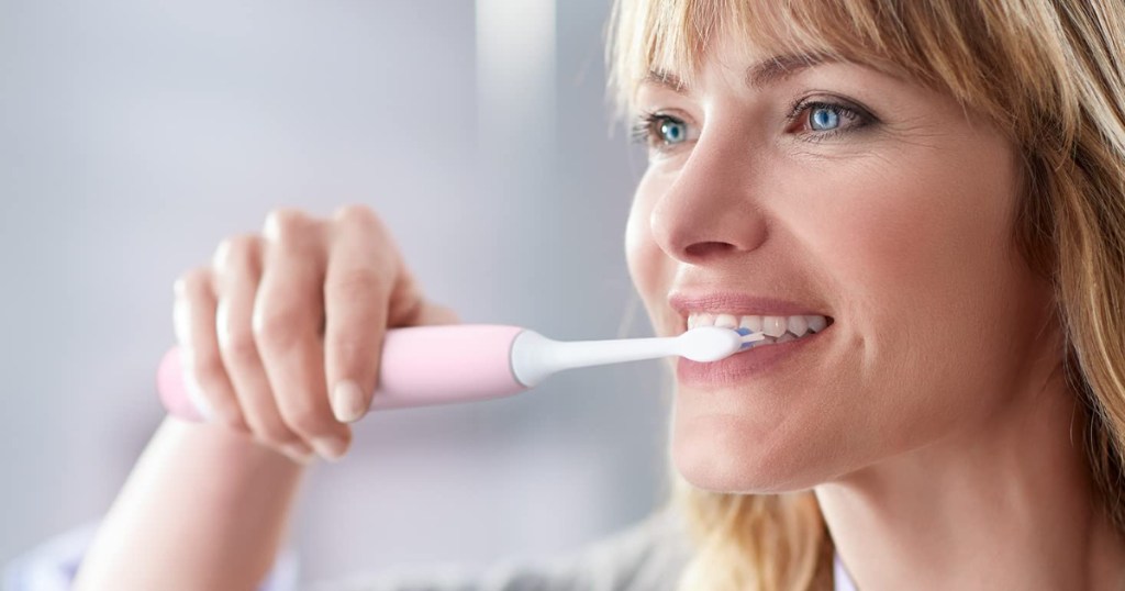 Woman brushing teeth with sonicare toothbrush