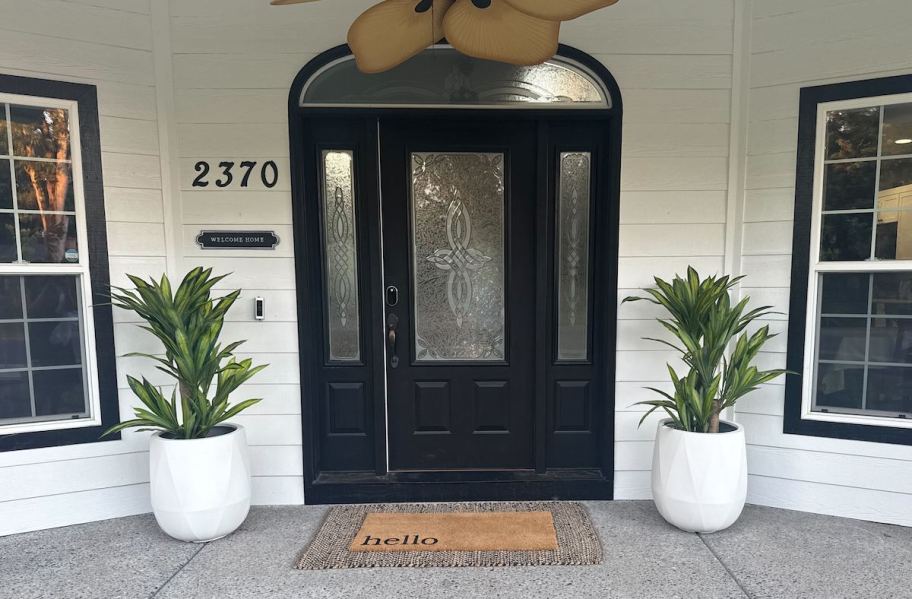front porch with white planters with faux trees