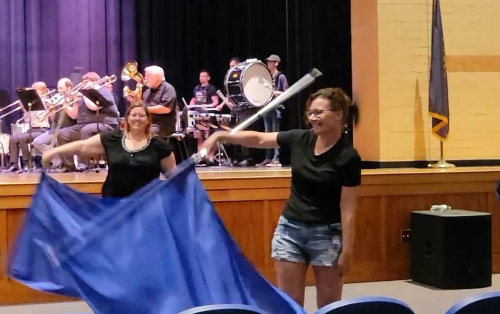 woman spinning color guard flag in auditorium