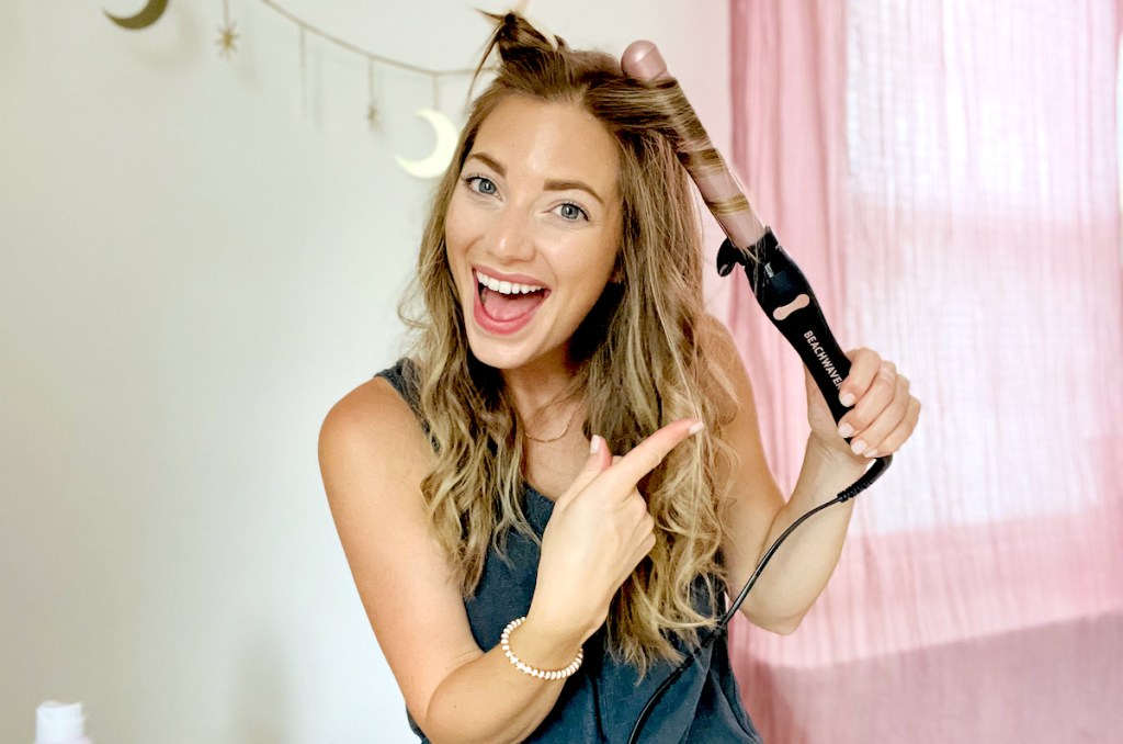 woman holding beachwaver curling iron on hair pointing to curls
