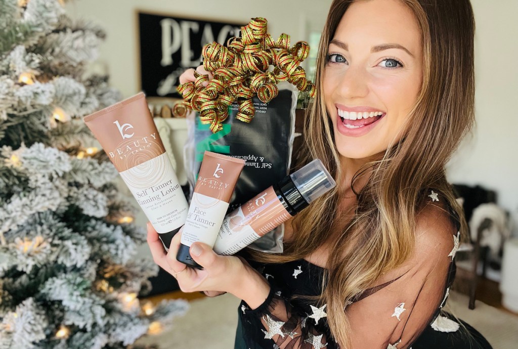 woman holding holiday bundle of beauty by earth self tanner