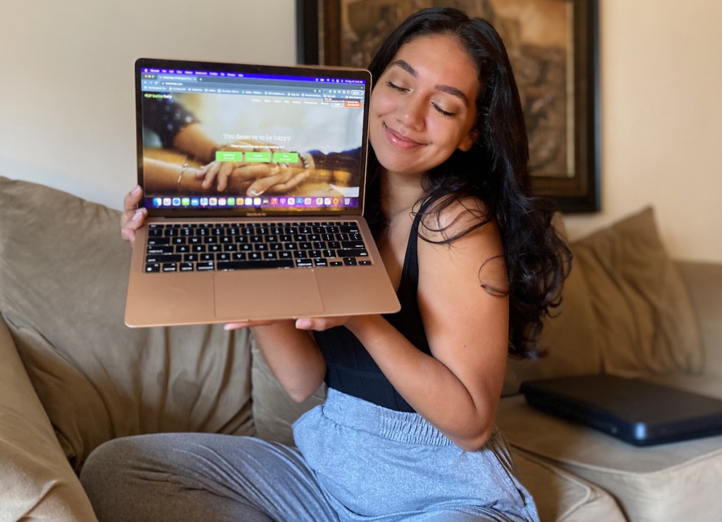 woman sitting on couch with eyes closed hugging apple laptop