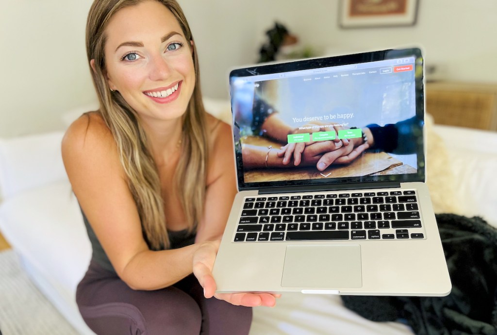 woman holding laptop with betterhelp therapy on screen
