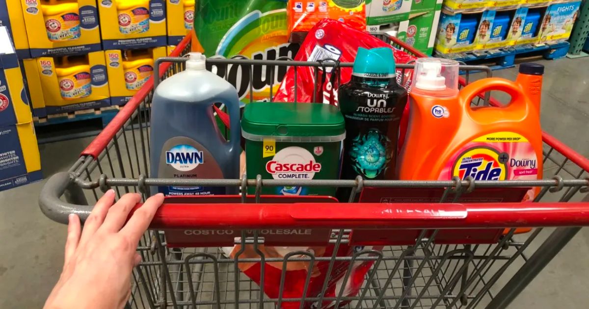 a womans hand pushing a costco cart with items 