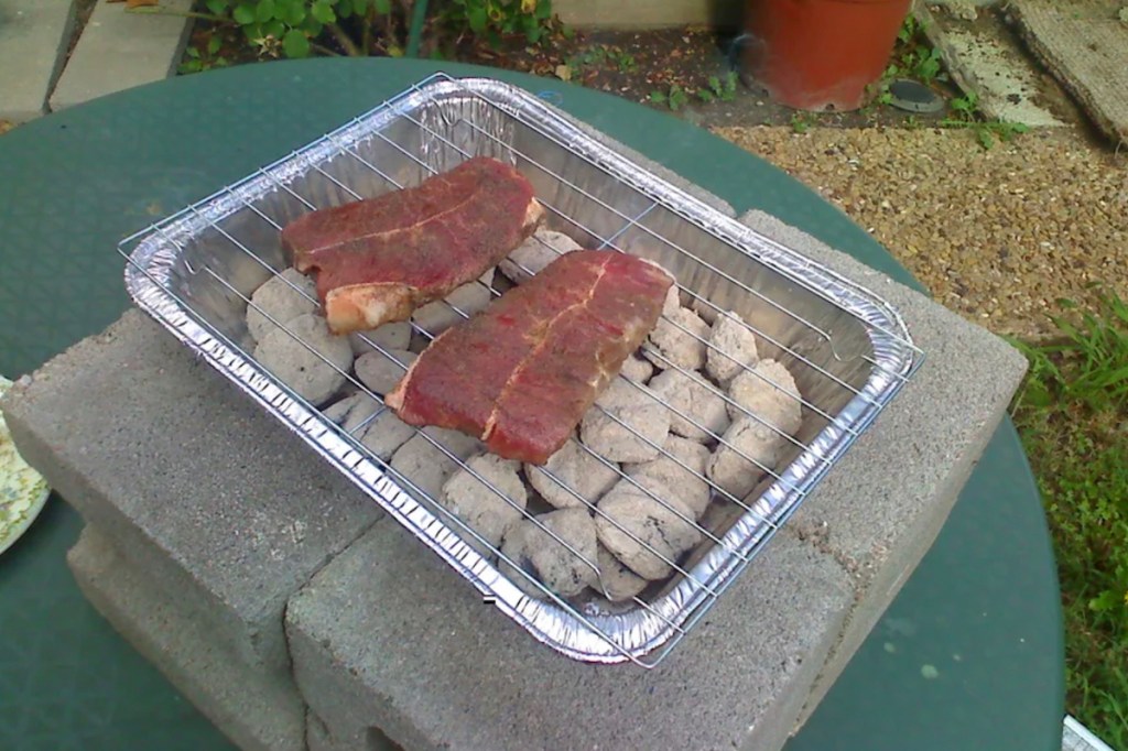 foil pan with charcoal and steaks for diy camping hacks grill