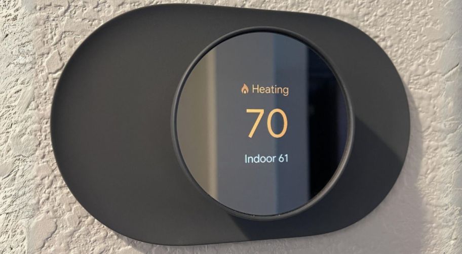 a charcoal colored google nest thermostat mounted on a beige wall
