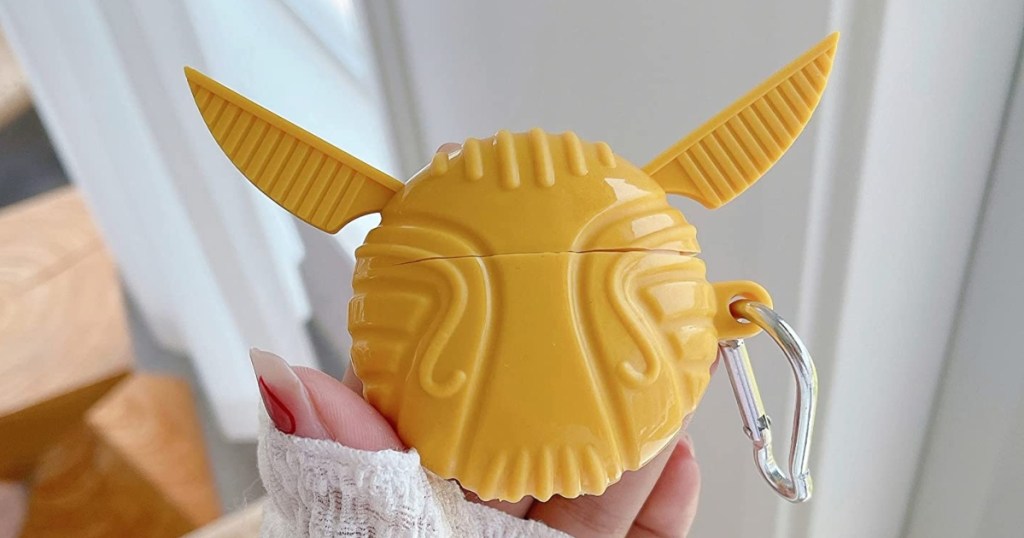 holding an AirPods case that looks like a golden snitch
