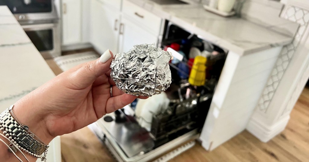 holding a ball of foil in front of dishwasher