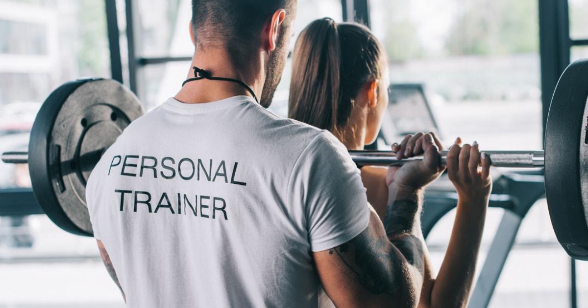personal trainer working with woman at gym