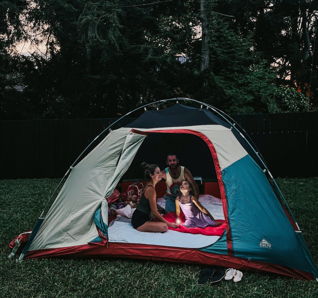 family sitting in tent outside in grass