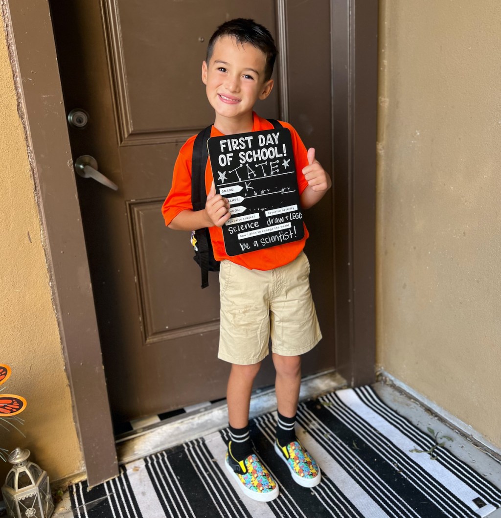 boy holding kindergarten sign with bookbag