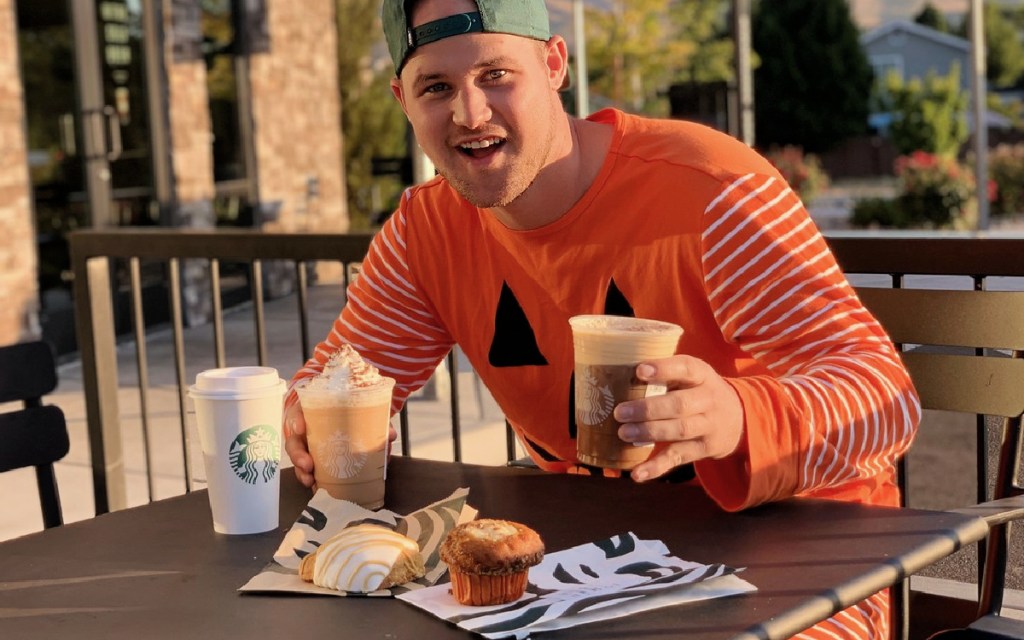 man in pumpkin suit holding starbucks drinks