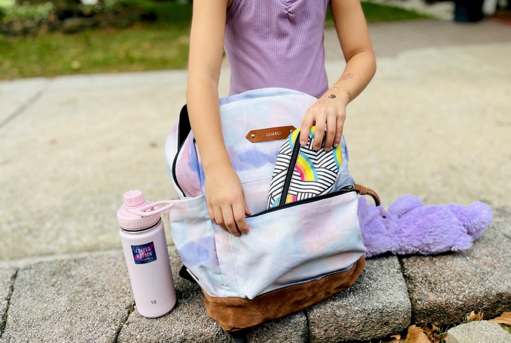 girl putting pencil case in tie-dye bookbag