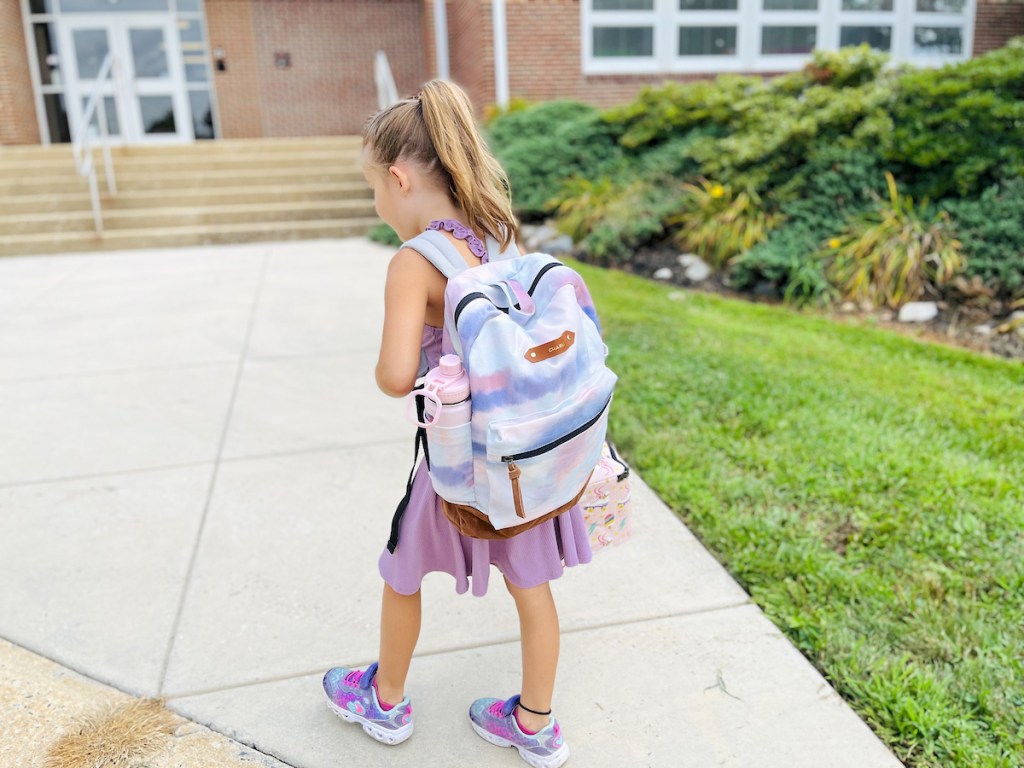 girl wearing tie dye bookbag walking into school