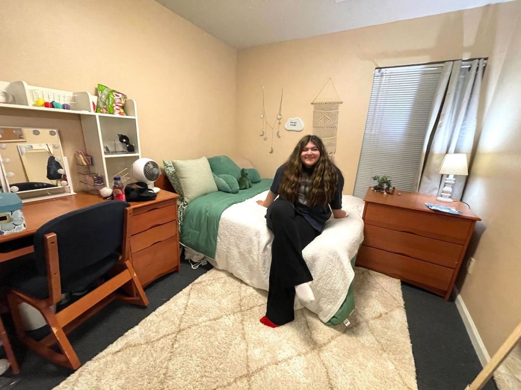 woman sitting on college dorm bed