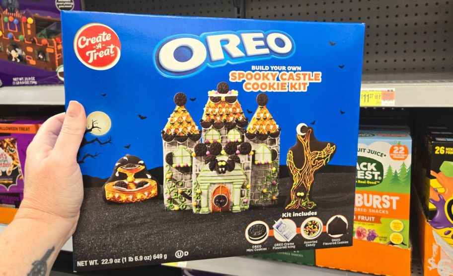 a womans hand holding a OREO halloween house cookie building kit