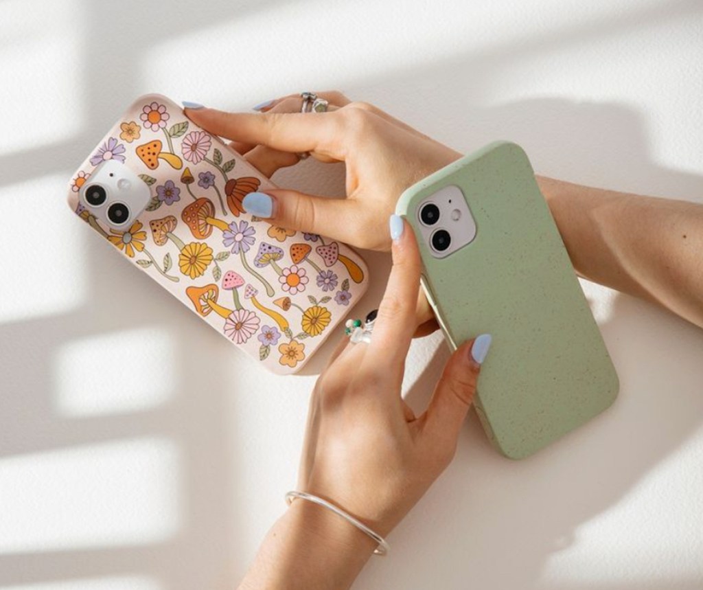 hands holding phones with green and mushroom floral covers