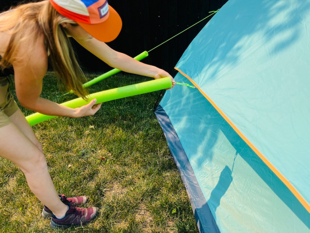 woman using pool noodles on tent strings for camping hacks and camping ideas