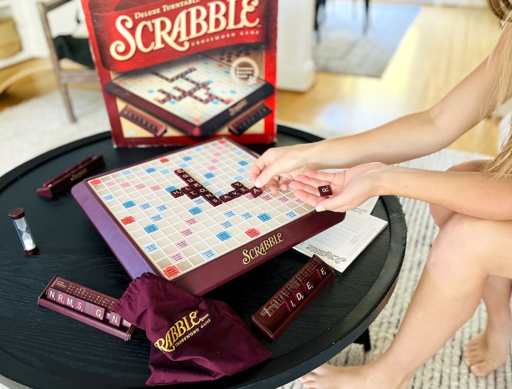 woman placing letters on scrabble board game 