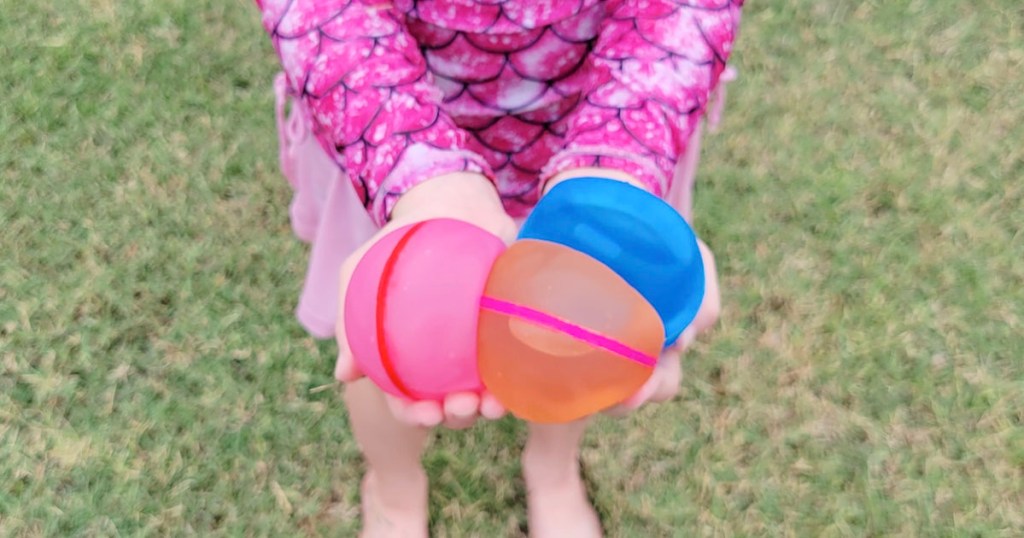 girl holding three water balloons