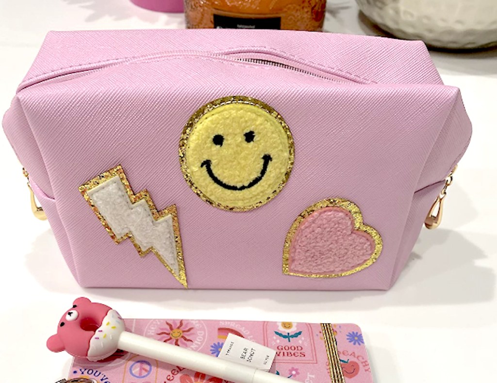 pink pouch bag with icon patches on front 