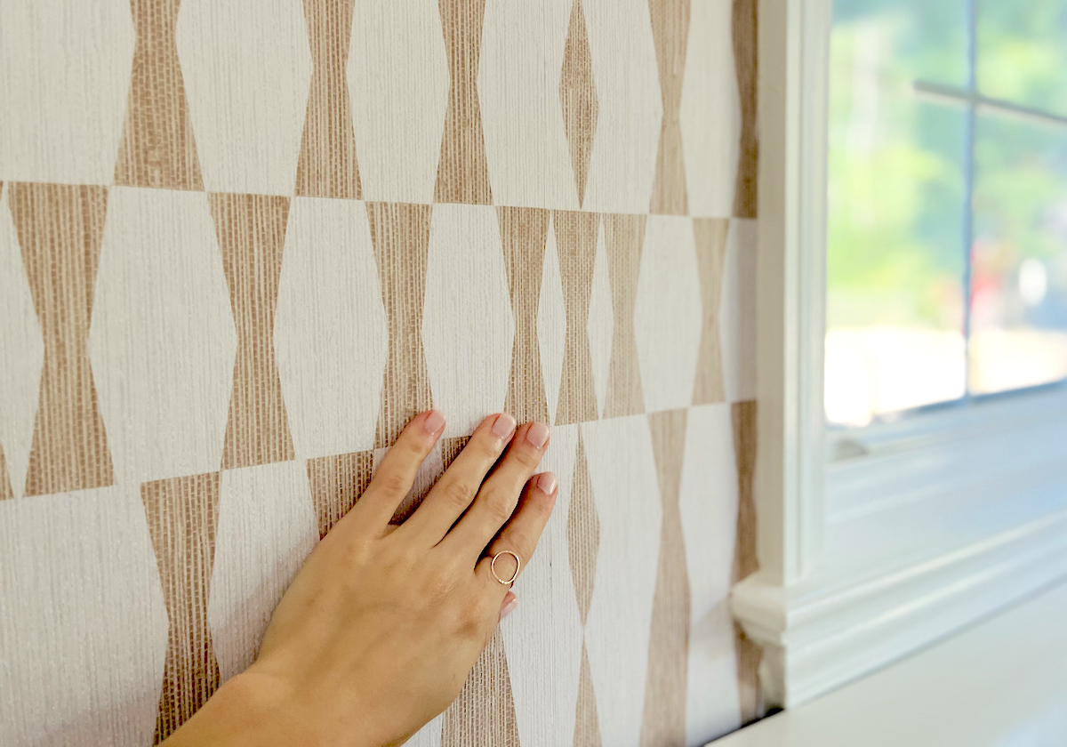 hand touching patterned texture wallpaper next to window