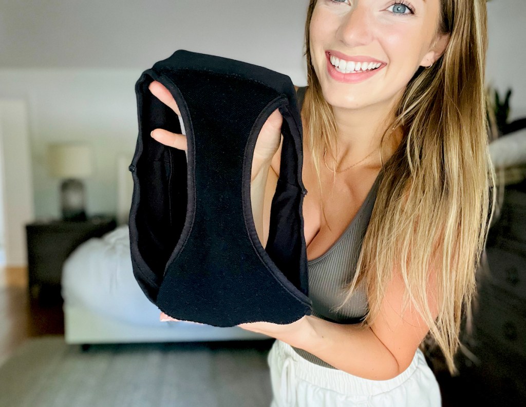 woman holding a pair of black thinx period panties smiling