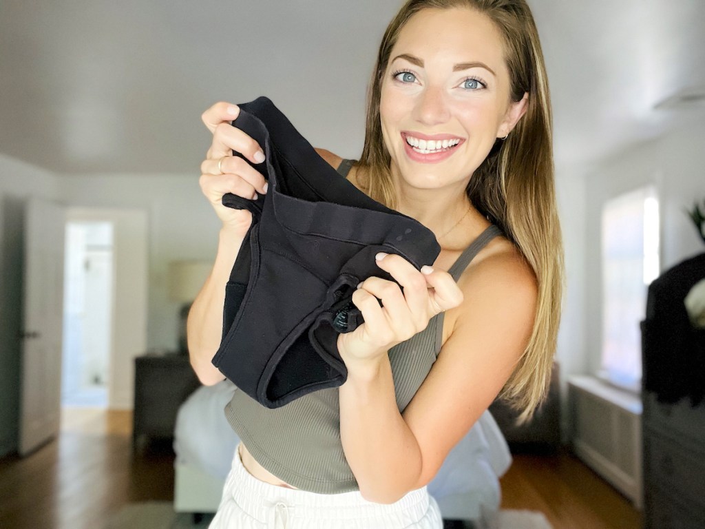 woman holding black pair of thinx for all period panties