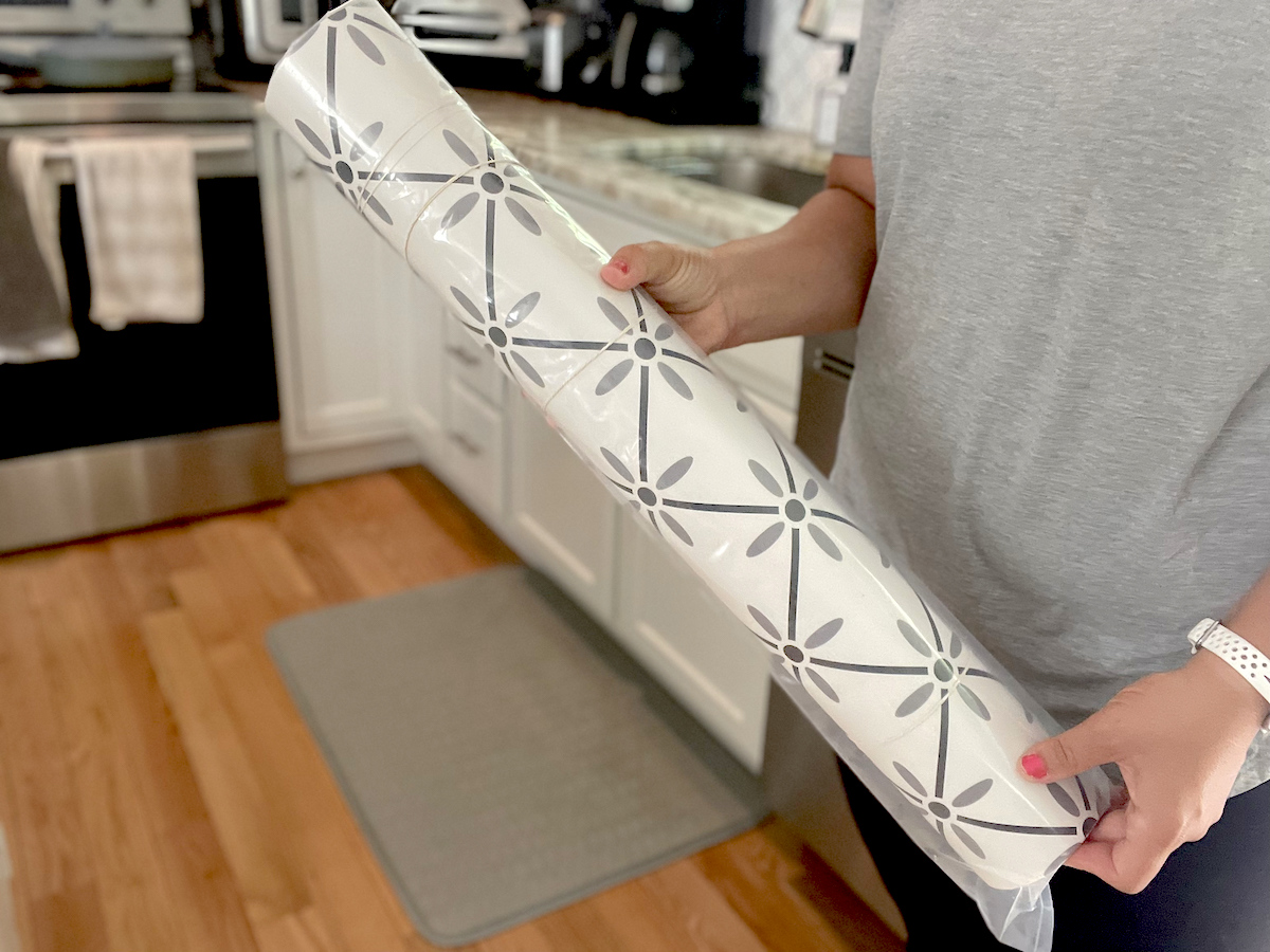 hand holding patterned mat rolled up in kitchen