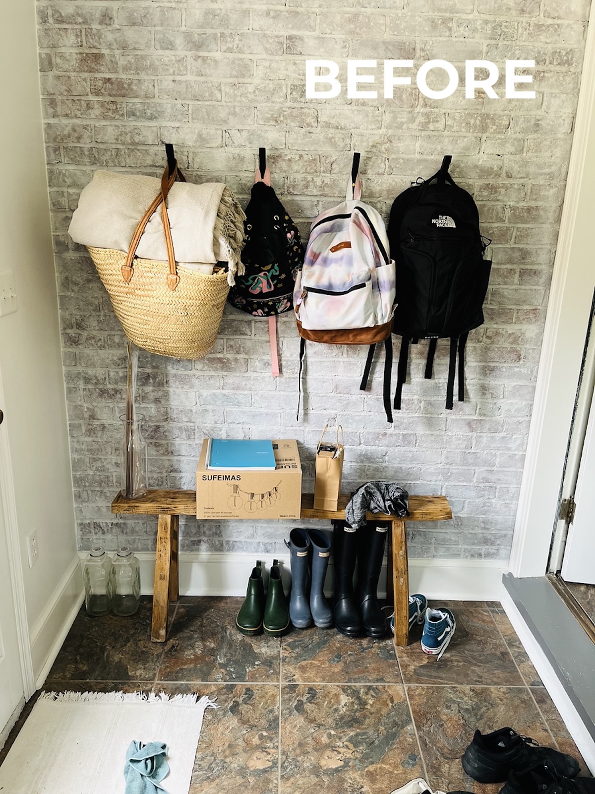 before of messy mudroom with book bags on hooks