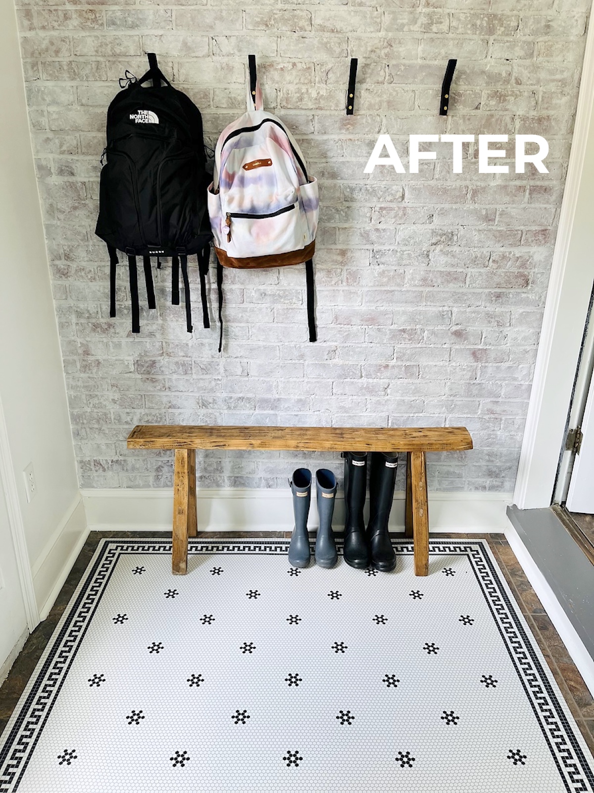 mudroom with black and white tile floor and book bags hanging up on hooks