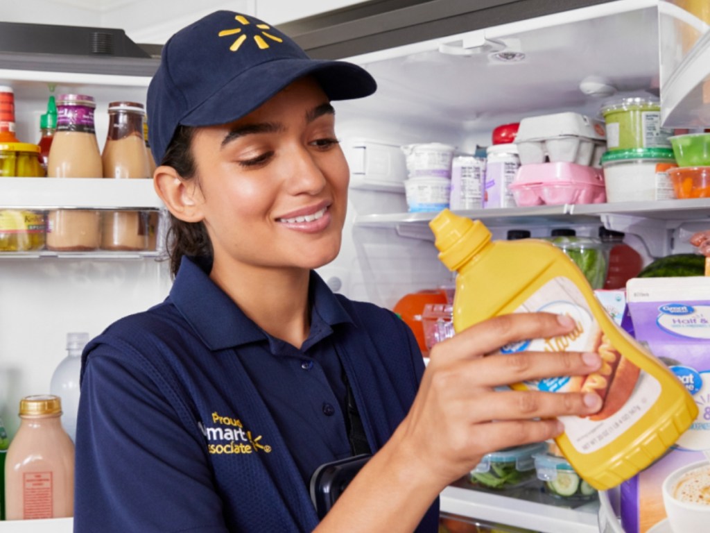 Walmart associate putting mustard in refrigerator