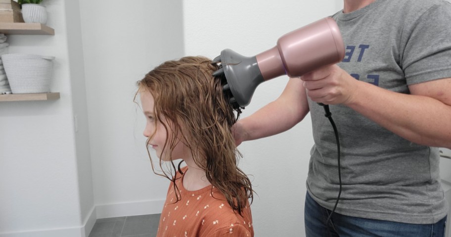 woman diffusing child's hair with pink and gray hair dryer
