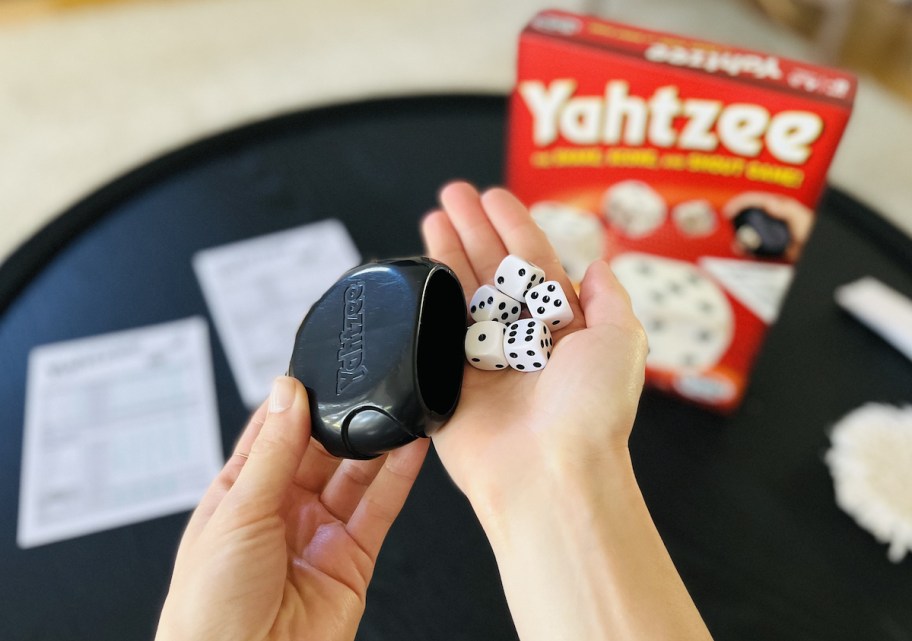 hands holding dice with yahtzee board game in background