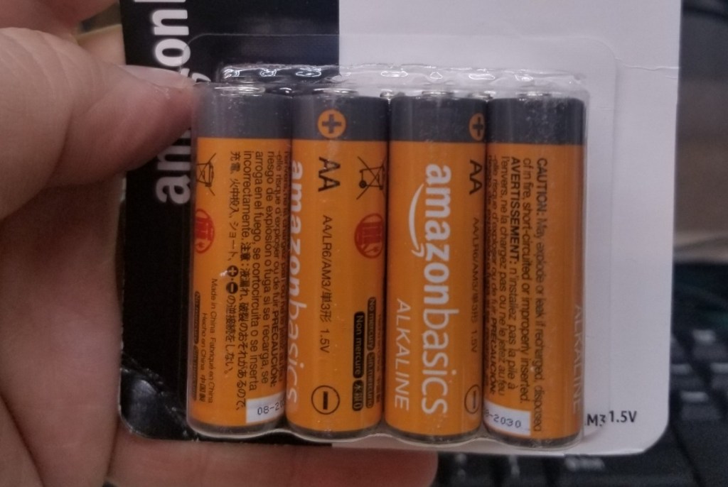 hand holding a package of Amazon Basics Batteries