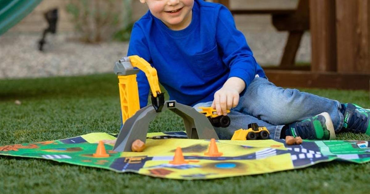 young boy playing with a cat little machines construction mat and truck